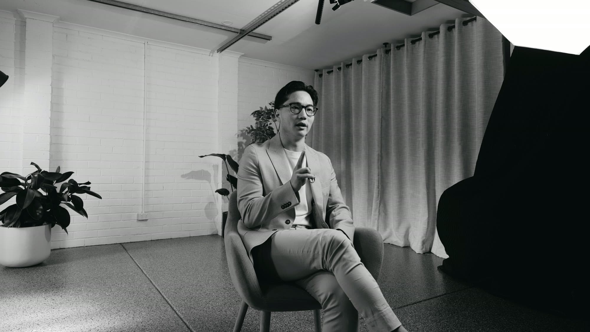 A real estate agent mid-interview under studio lighting, with the softbox and flag in shot